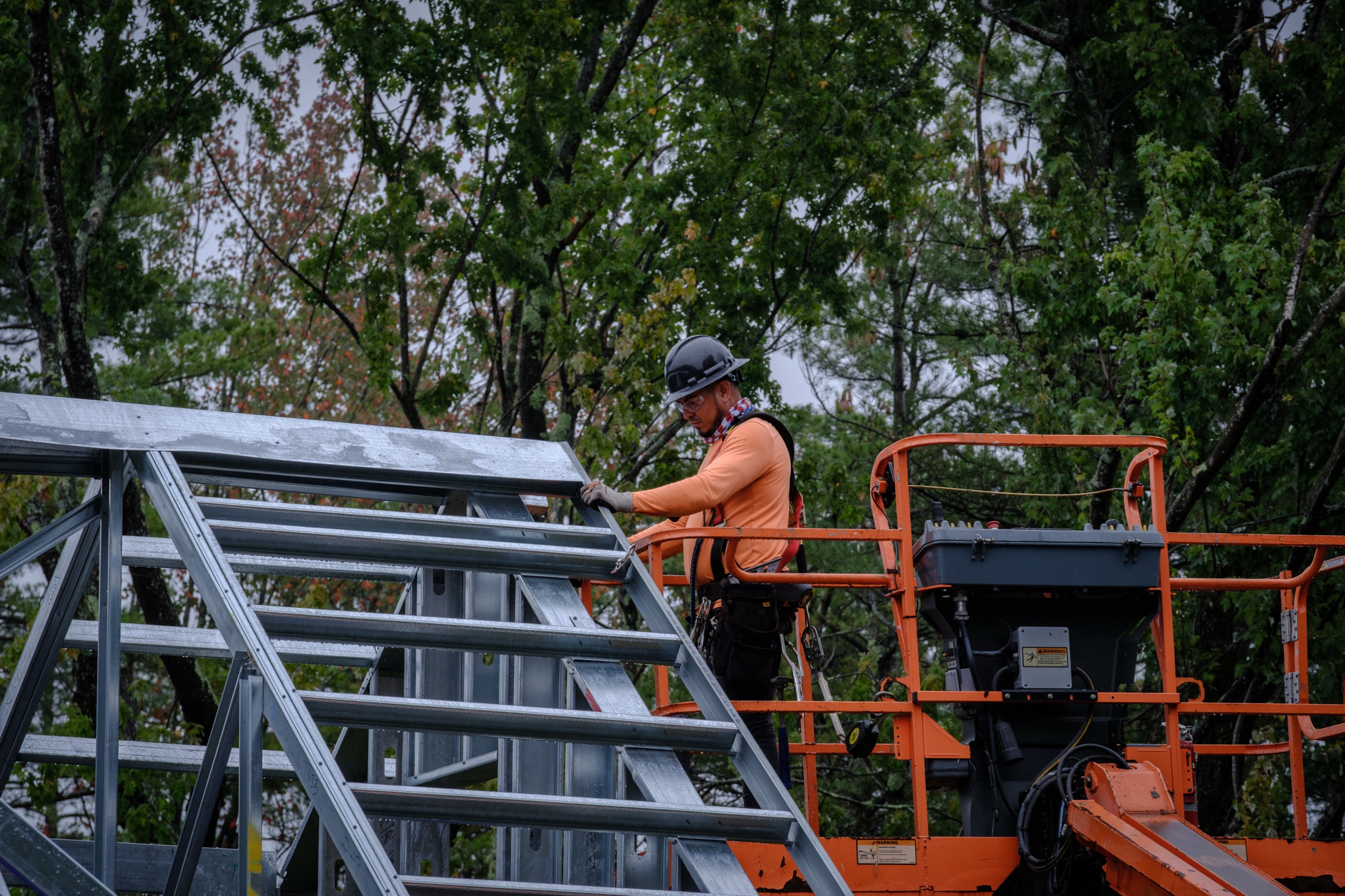 Worker on steel truss in cherry picker — construction photography by Bruce Peter Morin